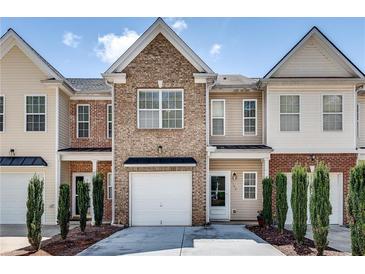 Charming townhome featuring a brick facade, attached garage, and well-maintained landscaping at 2968 Greyhawk Ln, Cumming, GA 30040
