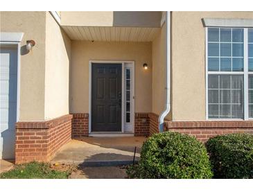 Charming front door entrance with brick accents, covered porch and manicured bushes at 2384 Coach Way, Jonesboro, GA 30236
