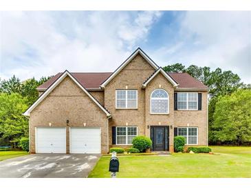 Charming two-story brick home featuring an attached two-car garage, well-manicured lawn and mature landscaping at 6990 Annie Walk, Lithonia, GA 30038
