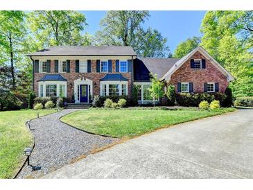 Charming brick home featuring a well-manicured lawn, mature trees, and a welcoming front entrance at 5023 Buckline Xing, Dunwoody, GA 30338