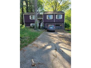 Two-story home with a two-car garage and a long driveway in a wooded surrounding at 6150 Silver Spur Dr, Lithonia, GA 30058