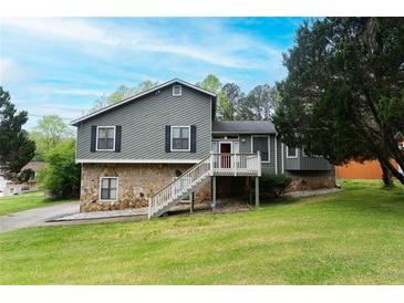 Split-level home featuring a stone foundation, gray siding, front stairs, and well-manicured lawn at 2015 Brookstone Ct, Lithia Springs, GA 30122