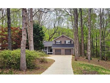 Charming two-story home with brown siding, a two-car garage, and a landscaped front yard surrounded by mature trees at 5415 Keithwood Dr, Cumming, GA 30040
