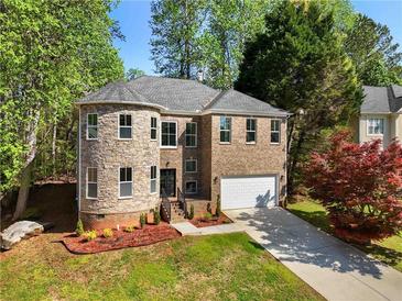 Charming two-story brick home with a turret-style stone accent and well-manicured lawn at 6960 Dockbridge Way, Stone Mountain, GA 30087