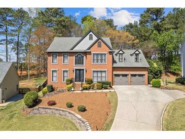 Charming two-story brick home with a well-manicured lawn and an attached two-car garage at 11570 Dunhill Place Dr, Johns Creek, GA 30005