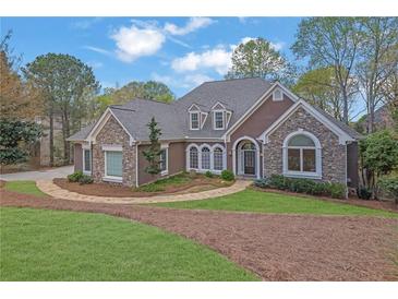 Stunning stone and stucco home with arched windows, dormers, landscaped yard and inviting pathway at 8385 Sentinae Chase Dr, Roswell, GA 30076