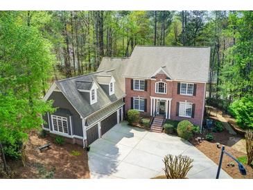 Charming two-story home featuring a brick facade and a well-manicured front yard surrounded by mature trees at 201 Rippling Nw Dr, Marietta, GA 30064