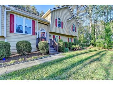 Charming two-story home with red shutters, a lush lawn, and mature landscaping offering great curb appeal at 6040 Carriage Dr, Cumming, GA 30028
