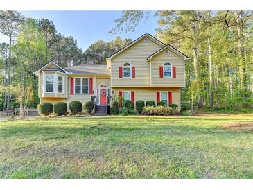 Charming home featuring a manicured lawn, classic architectural details, and bright red window shutters at 6040 Carriage Dr, Cumming, GA 30028