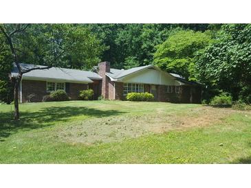 Quaint brick home with a chimney and a lush green lawn surrounded by mature trees at 1256 E Piedmont Rd, Marietta, GA 30062