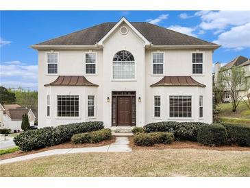 Stucco two-story home with manicured landscaping and a dark roof under a blue sky at 6028 Connaught Se Dr, Mableton, GA 30126