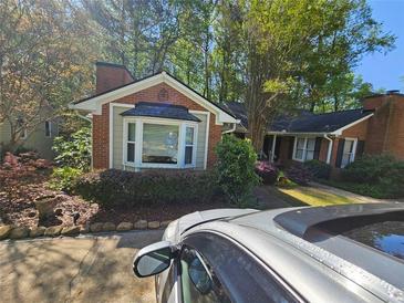 Charming home exterior featuring brick accents, bay window, and lush landscaping at 1910 Cooper Landing Se Dr, Smyrna, GA 30080