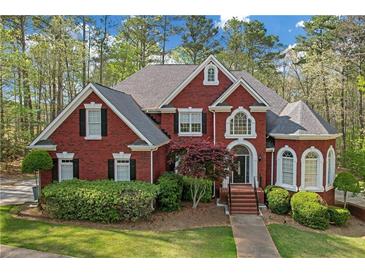 Charming red brick home featuring a manicured lawn, mature trees, and well-maintained landscaping at 240 River Cove Mdws, Social Circle, GA 30025