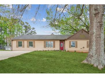 Charming single-story home featuring a well-maintained lawn and a welcoming red front door at 140 Apple Valley Dr, Woodstock, GA 30188