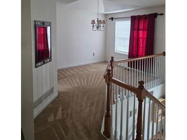 View of living room with red curtains, staircase, chandelier and neutral-colored carpet at 204 Millpond Pkwy, Villa Rica, GA 30180