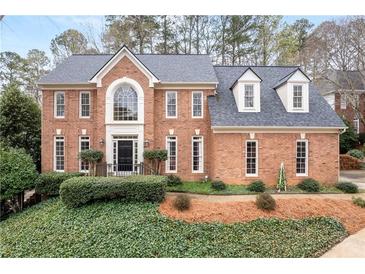 Stunning two-story brick home with a manicured front yard and classic architectural details at 205 Wellesley Ct, Woodstock, GA 30189