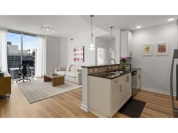 Bright living room with a modern kitchen, a comfortable sofa, and a large window with city views at 855 Peachtree Ne St # 2706, Atlanta, GA 30308