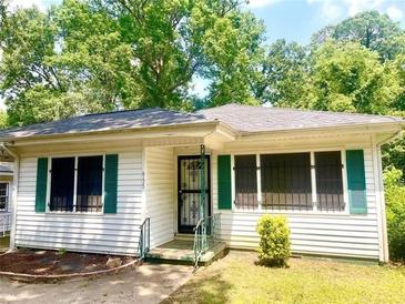 Charming single-story home with white siding and green shutters, set among mature trees at 955 Margaret Nw Pl, Atlanta, GA 30318