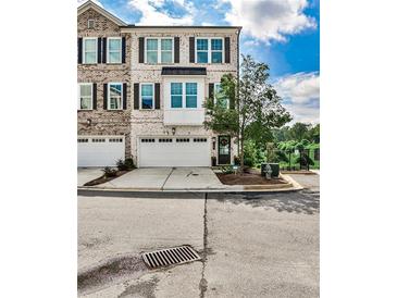 Charming brick townhome with a two-car garage, complemented by manicured landscaping and beautiful architectural details at 125 Sidney St, Marietta, GA 30060