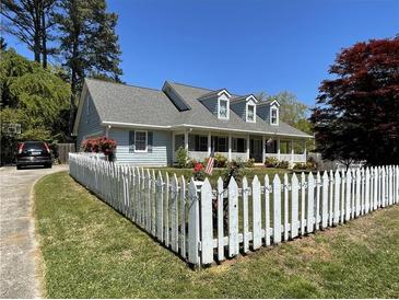 Charming home featuring a white picket fence, manicured lawn, and covered porch at 5167 Manitu Sw Ct, Lilburn, GA 30047
