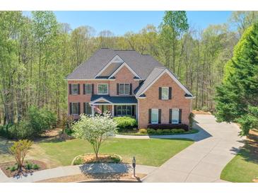 Beautiful two-story brick home with a well-manicured lawn and a long driveway surrounded by lush greenery at 205 Northampton Ct, Canton, GA 30115