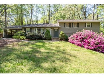 Charming home featuring a lush lawn, blooming azaleas, and a convenient covered carport at 380 Amberidge Trl, Atlanta, GA 30328