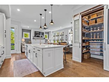 Bright kitchen features a large island with a white countertop and a walk-in pantry with sliding doors at 7515 Cordery Rd, Cumming, GA 30040