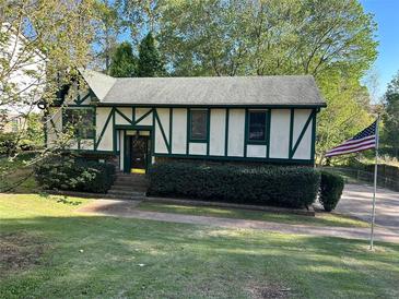 Charming Tudor-style home with green trim, manicured hedges, and American flag at 4152 Scenic Mountain Dr, Snellville, GA 30039