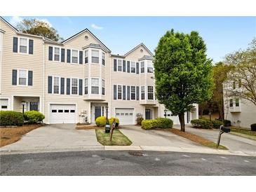 Townhouse exterior with individual garages, blue shutters, and well-kept landscaping at 5213 Pinnacle Point Ct, Norcross, GA 30071