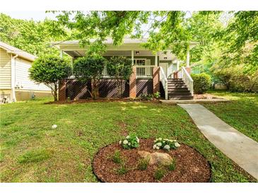 Charming home featuring a inviting front porch, landscaped yard, and stone walkway at 1412 Woodbine Se Ave, Atlanta, GA 30317