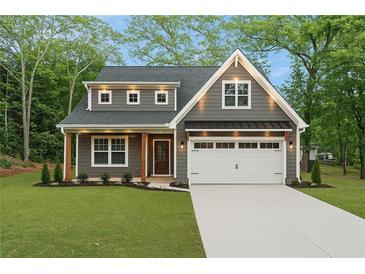 Charming two-story home featuring gray siding, a well-manicured lawn, and an attached two-car garage at 5260 Moore St, Stone Mountain, GA 30083