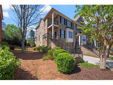 Charming multi-story townhome featuring stone and brick facade, small balconies and landscaped front yard at 1016 Manchester Way # 43, Roswell, GA 30075