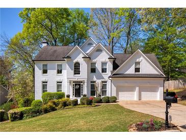 Beautiful white brick two-story home with a well-manicured lawn and a two-car garage at 125 Ketton Xing, Johns Creek, GA 30097
