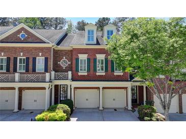 Charming red brick townhome featuring a two-car garage, classic design, and well-maintained landscaping at 7512 Portbury Park Ln, Suwanee, GA 30024