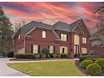 Stunning two-story brick home featuring manicured lawn and a warm, inviting facade at sunset at 9250 Nesbit Lakes Dr, Alpharetta, GA 30022