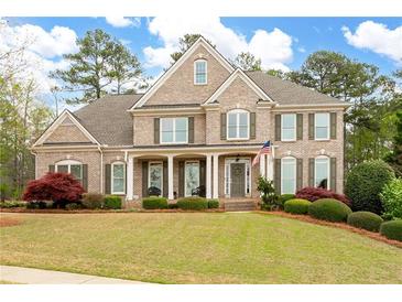 Charming two-story brick home boasts a well-manicured lawn, shutters, and welcoming front porch at 111 Glen Trl, Woodstock, GA 30188