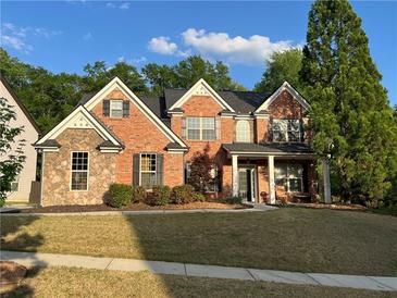 Charming brick two-story home with stone accents, landscaped yard, and covered front porch at 2964 Olivine Dr, Dacula, GA 30019