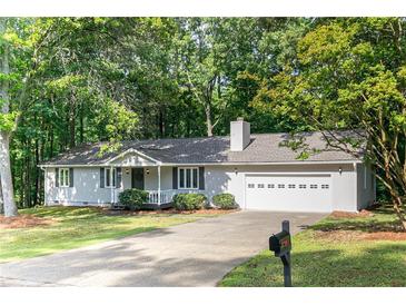 Charming home featuring a two-car garage and a beautifully maintained front yard with mature trees at 5819 Stonehaven Nw Dr, Kennesaw, GA 30152