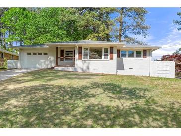 Charming one-story home featuring white painted brick, a well-manicured lawn and an attached garage at 2461 Antwerp Se Dr, Atlanta, GA 30315