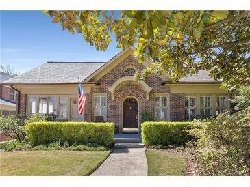 Charming brick home featuring manicured landscaping, arched entryway, and an American flag at 1285 Oakdale Ne Rd, Atlanta, GA 30307