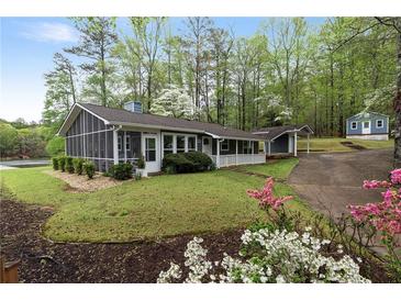 Charming home exterior with a screened porch, well-maintained lawn, and lush landscaping showcasing curb appeal at 7650 Rico Rd, Chattahoochee Hills, GA 30268