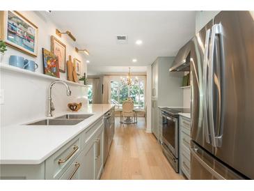 Modern kitchen features stainless steel appliances, light cabinetry with gold hardware, and a view to the dining area at 39 Ivy Gates Ne, Atlanta, GA 30342