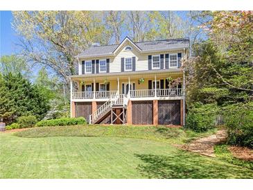 Inviting two-story home featuring a charming front porch, a well-maintained lawn, and mature trees at 4520 Windsor Oaks Dr, Marietta, GA 30066
