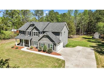 Beautiful gray two-story home featuring a charming covered porch, lush lawn and long driveway at 719 Fairview Rd, Brooks, GA 30205