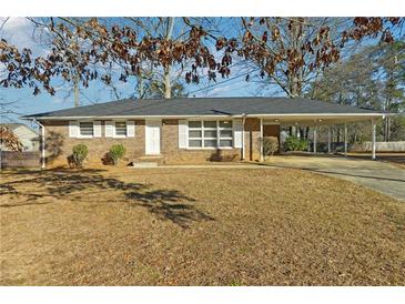 Charming brick home with a covered parking area and a well-maintained front yard at 8586 Taylor Rd, Riverdale, GA 30274