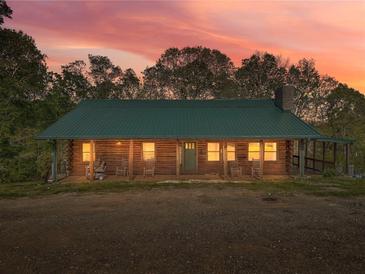 Charming cabin illuminated at twilight, surrounded by lush trees; a serene retreat at 1288 Reavesville Rd, Bowdon, GA 30108