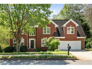 Charming two-story brick home with a well-manicured lawn, mature tree, and attached two-car garage at 1755 Pinetree Pass Sw Ln, Lilburn, GA 30047