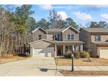 Charming two-story home featuring a brick and stone facade, attached two-car garage, and inviting front porch at 75 Glen Abbey Cir, Fairburn, GA 30213