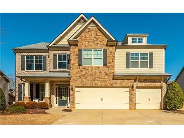 Inviting two-story home featuring brick and stone facade, complemented by a three-car garage and manicured lawn at 5390 Chestnut Dr, Cumming, GA 30040