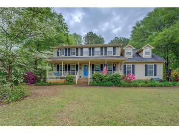 Charming two-story home with a welcoming front porch, American flag and landscaped yard at 293 Country Lake Dr, Mcdonough, GA 30252